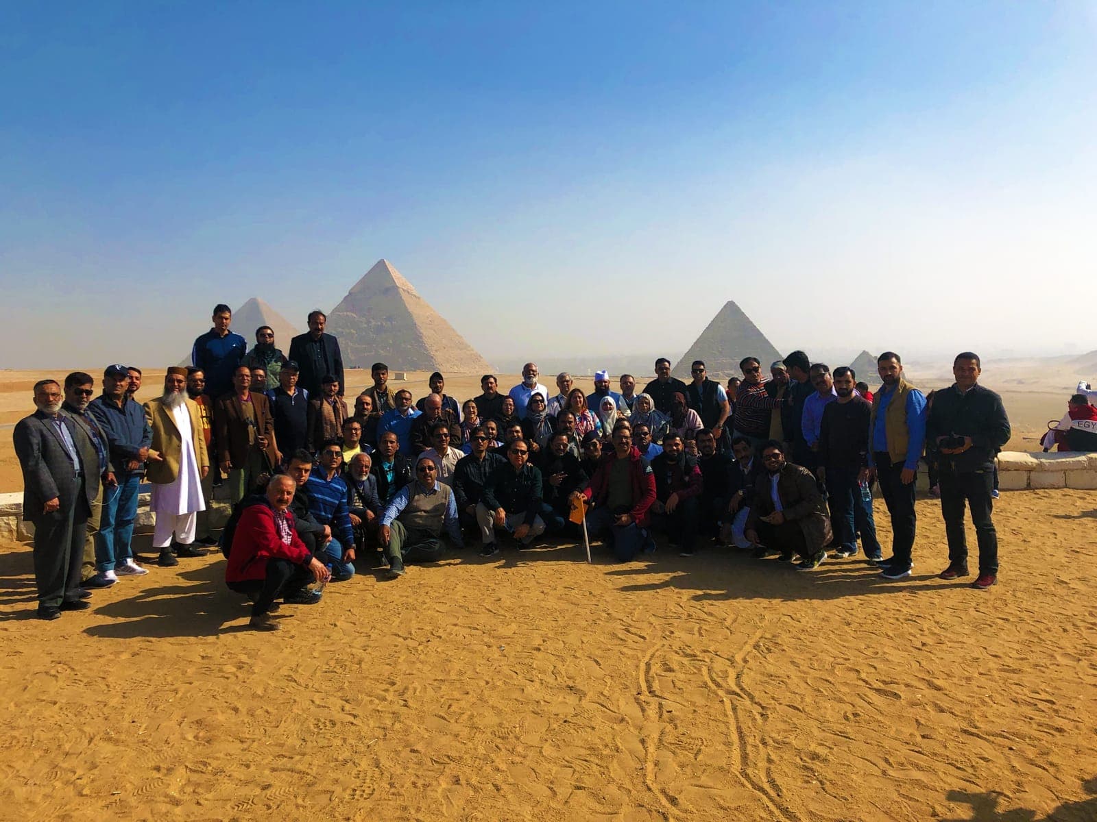 An IBEX group photographed on the Giza plateau with the pyramids behind them