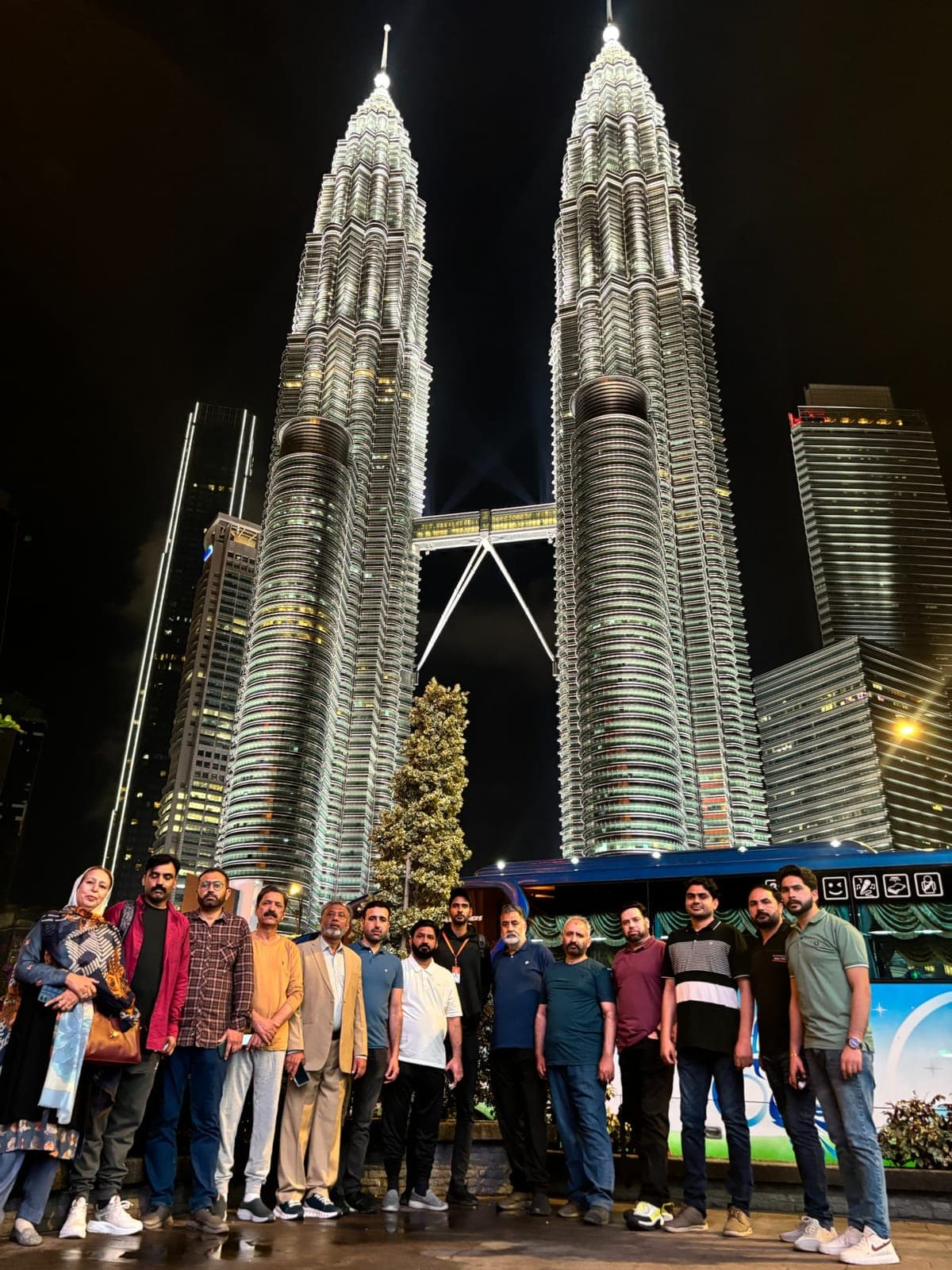 An IBEX group photographed at night beneath the lit Petronas Twin Towers in Kuala Lumpur